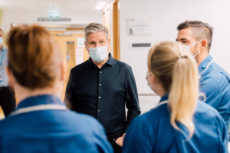 Keir Starmer wearing a facemask with three nurses