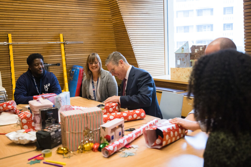 Keir Starmer wrapping Christmas presents at a table with three other people