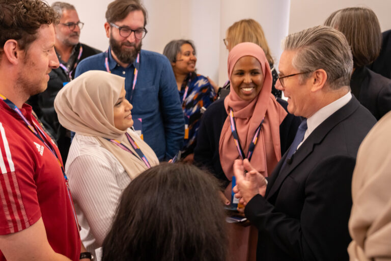 Keir Starmer surrounded by people smiling at indoor event